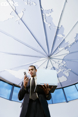 Low angle view of a businessman holding a mobile phone and a laptop